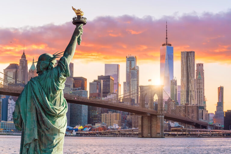 Statue Liberty and New York city skyline at sunset, in United States